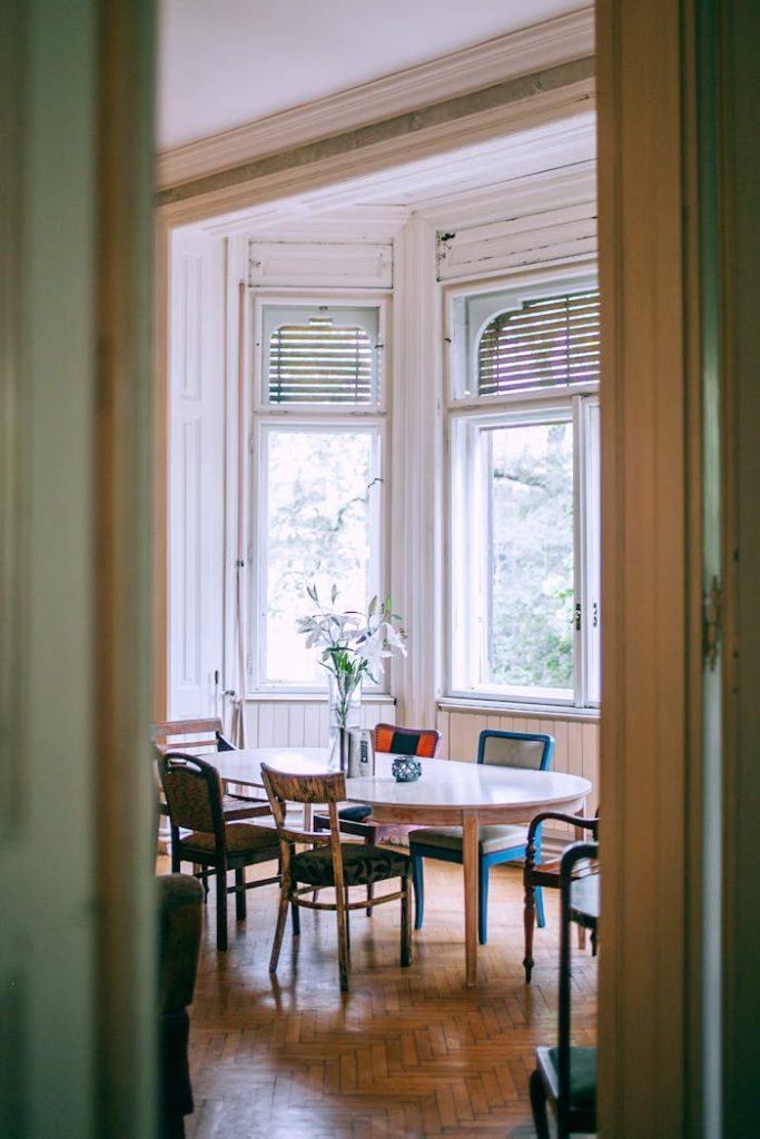 A cozy, vintage-style dining room with large windows and elegant decor, providing a peaceful atmosphere.